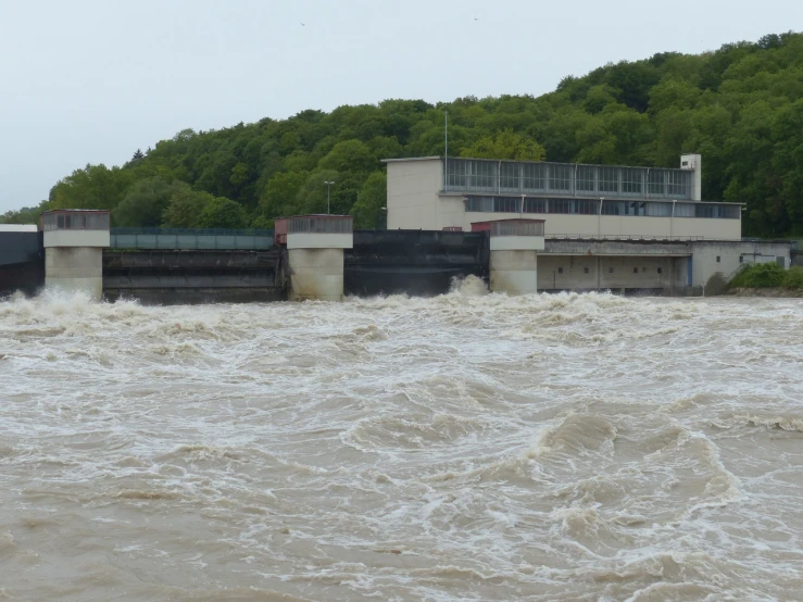 a large body of water with a building in the background, a picture, shin hanga, rushing water, turbines, water levels, lock