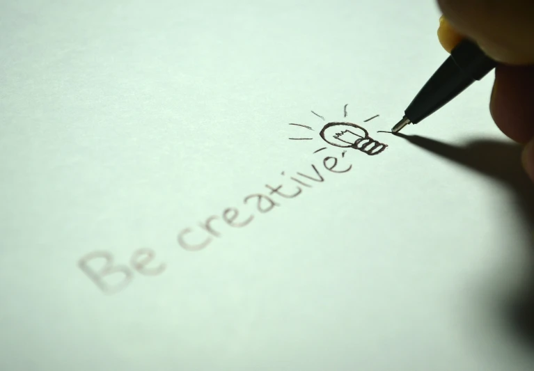 a person writing on a piece of paper with a pen, a picture, trending on pixabay, graffiti, light bulb, creative commons attribution, creative fashion, words