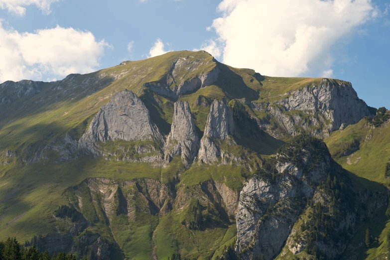 a group of sheep standing on top of a lush green hillside, a picture, by Cedric Peyravernay, figuration libre, sharp cliffs, mount olympus, detailed 4 k photo, seen from a distance