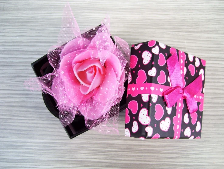 a pink rose sitting inside of a black gift box, by Susan Heidi, flickr, black and white with hearts, covered with pink marzipan, gifts, side-view