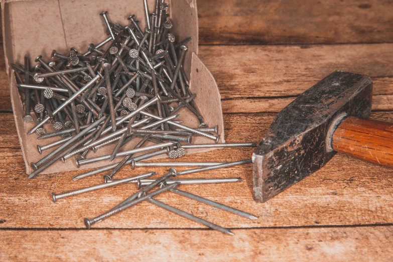 a box of nails and a hammer on a table, high detail product photo, close-up product photo, long metal spikes, detailed product photo