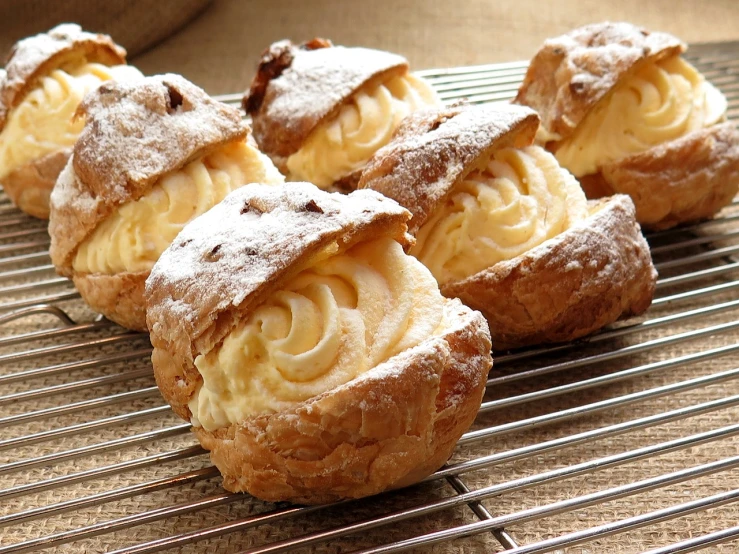 a group of pastries sitting on top of a cooling rack, shutterstock, baroque, cream, thick lining, hasbulla, rustic