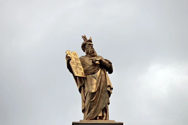 a statue of a man with a crown on top of a building, a statue, by Vincenzo Cabianca, baroque, wizard reading a directory, standing in gold foil, focused photo, moses