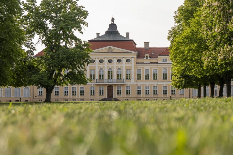 a large building sitting on top of a lush green field, a picture, by Dietmar Damerau, shutterstock, danube school, front face, palace background, pov photo, lifestyle