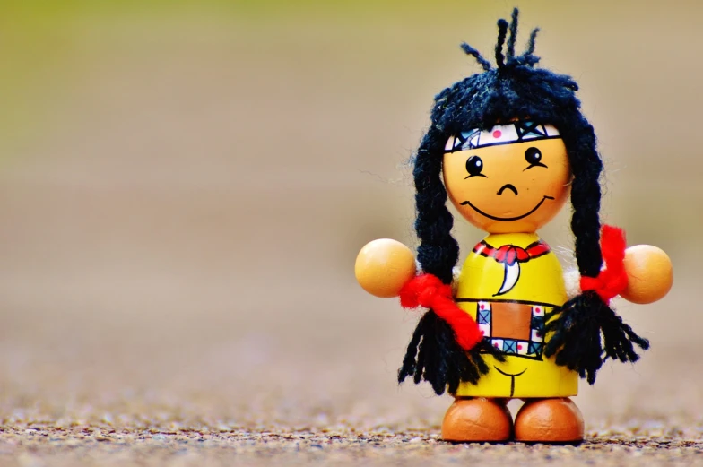 a close up of a doll on the ground, a cartoon, by Jesper Knudsen, trending on pixabay, figuration libre, indian warrior, proud smile, with a wooden stuff, a girl playing tennis