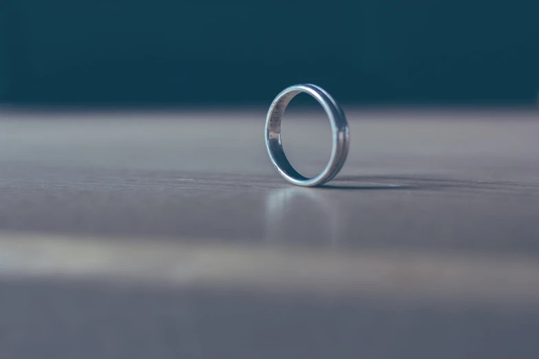 a close up of a wedding ring on a table, a tilt shift photo, minimalism, 3d-render, the futility of overexertion, stainless steal, mid shot photo