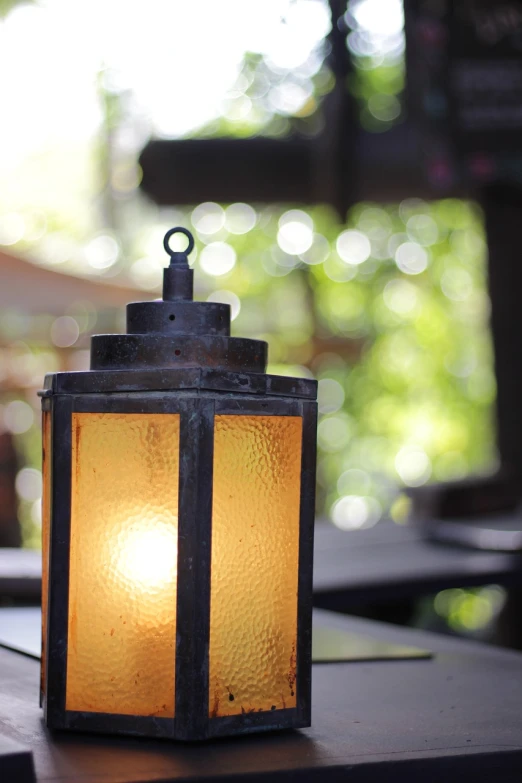 a lantern sitting on top of a wooden table, realism, soft blur outdoor lighting, bokeh photo