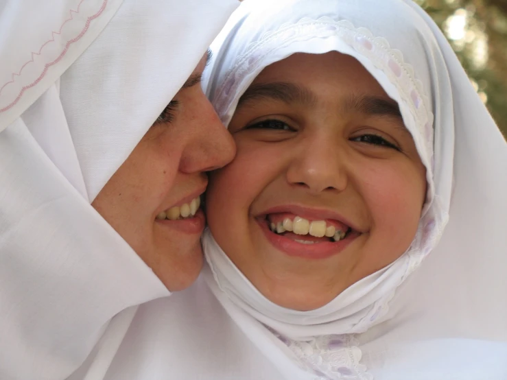 a close up of a person wearing a headscarf, by Maryam Hashemi, flickr, hurufiyya, smiling girl, hugging each other, wearing white cloths, with a kid