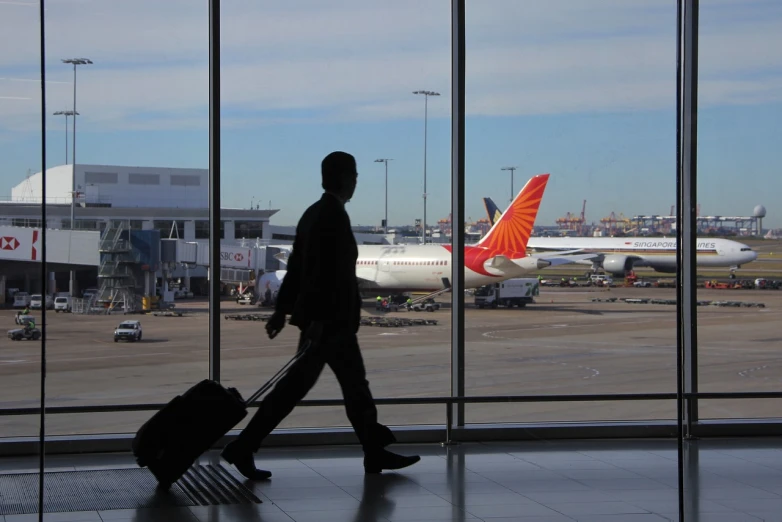 a man walking through an airport with a suitcase, a picture, india, a phoenix, afp, sydney