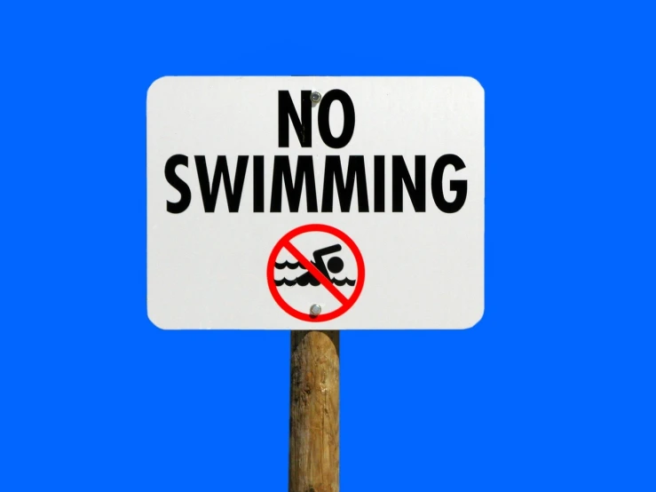 a no swimming sign on a pole against a blue sky, a photo, by Whitney Sherman, shutterstock, photo-shopped, body in water, no bricks, oscar winning
