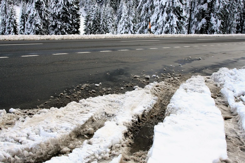 a road covered in snow next to a forest, a photo, by Alfons von Czibulka, shutterstock, wet asphalt, digging, salt, trim