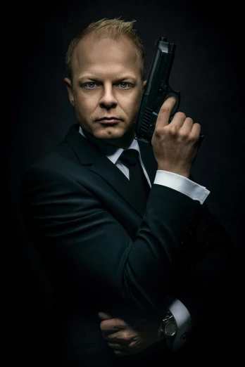 a man in a suit holding a gun, a character portrait, by Emma Andijewska, shutterstock, shot in the photo studio, james bond, simon pegg portrait, ultra realistic masterpiece