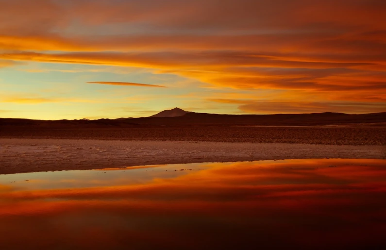 a large body of water with a mountain in the background, a picture, by Niklaus Manuel, shutterstock, romanticism, burning red desert horizon, amazing color photograph, chocolate, chris moore”