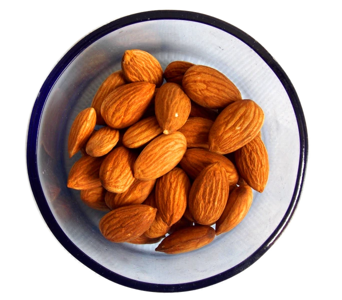 a bowl filled with almonds sitting on top of a table, by David Garner, wikimedia, view from bottom to top, on white, kiss