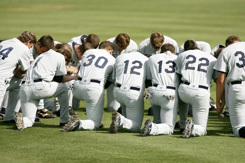 a group of baseball players kneeling in a huddle, a photo, by Emanuel Witz, shutterstock, doing a prayer, marker”, college, 2 0 0 0's photo