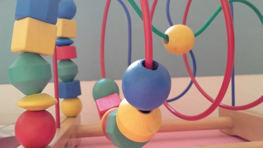 a close up of a toy on a table, flickr, solid coloured shapes, rack, serpentine curve!!!, beads