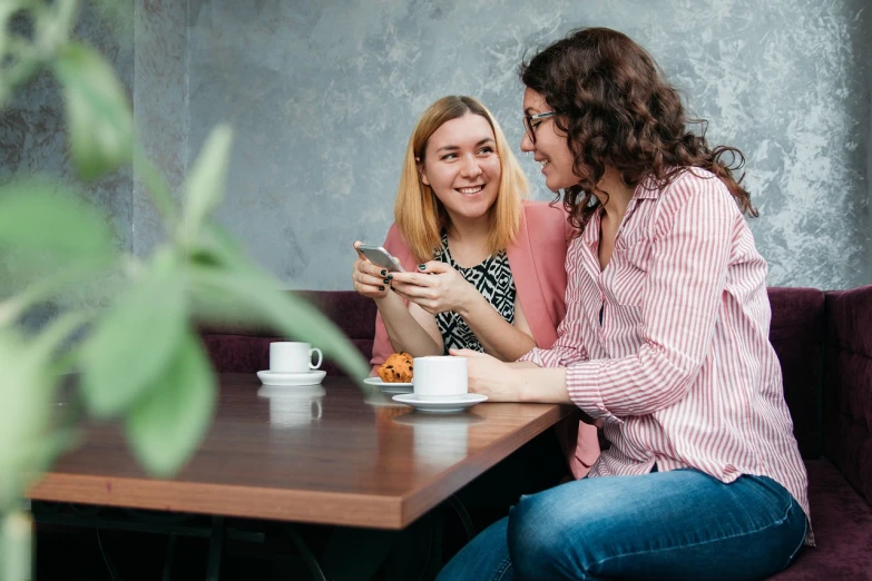 two women sitting at a table looking at a cell phone, a portrait, by Zofia Stryjenska, shutterstock, cheerful atmosphere, hidden camera photo, ukrainian, stock photo