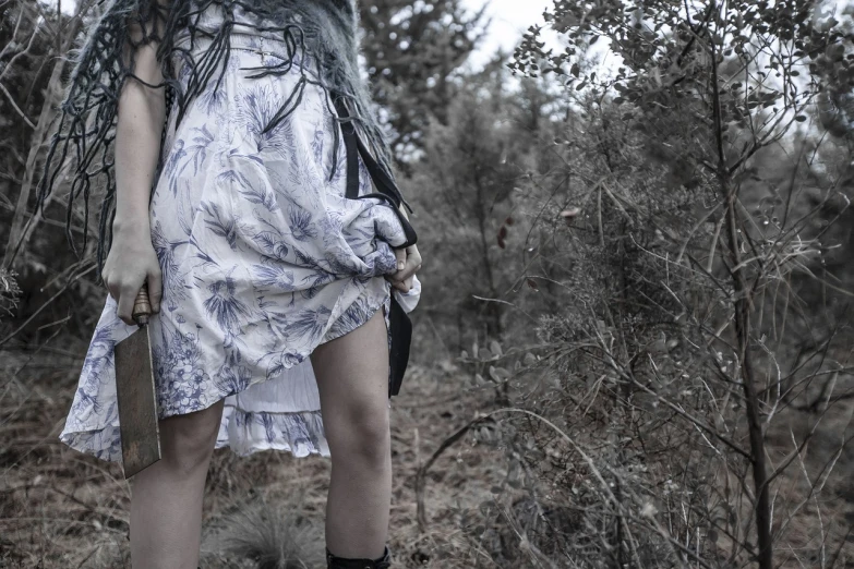 a woman standing in the middle of a forest, a portrait, tumblr, dressed in a frilly ((ragged)), blue and grey tones, leg shot, warpaint aesthetic