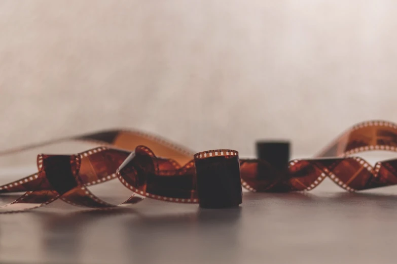 a roll of film sitting on top of a table, by Emma Andijewska, pexels, video art, 1920s film, movie inspired, live action film, celluloid