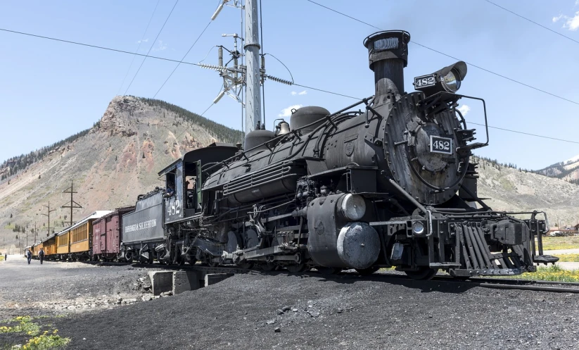 a train traveling down train tracks next to a mountain, a portrait, oversized enginee, # 4 2 0, coal dust, rtx engine