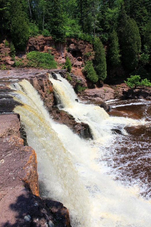 a large waterfall in the middle of a forest, a photo, red sandstone natural sculptures, quebec, tourist photo, usa-sep 20