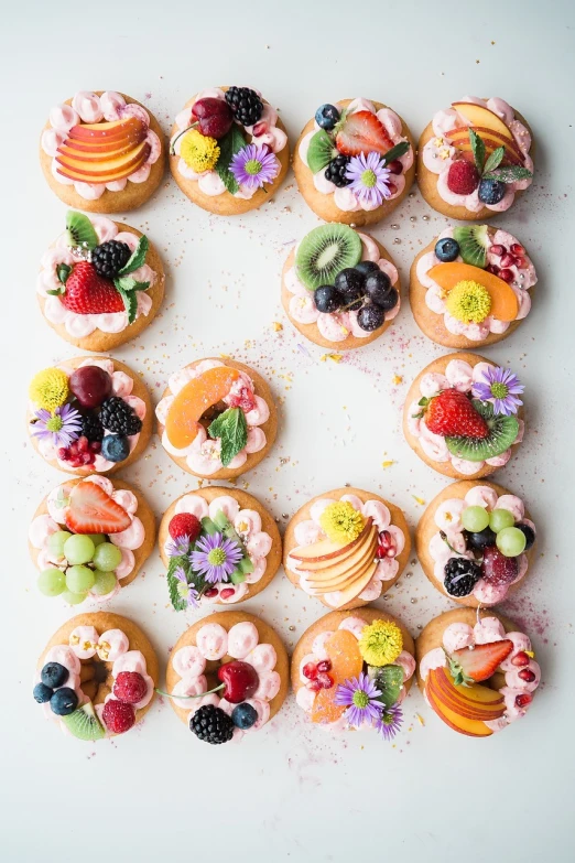 a white table topped with donuts covered in fruit, a pastel, by Anna Haifisch, pexels, decorated with flowers, beautiful!!!!!!!!!!!!, many small details, 9