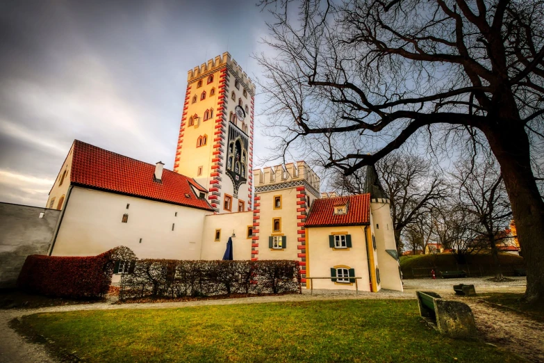 a large building with a clock tower in the background, by Oskar Lüthy, shutterstock, inner ward of a medieval castle, white buildings with red roofs, hdr photo, 35mm wide angle photograph