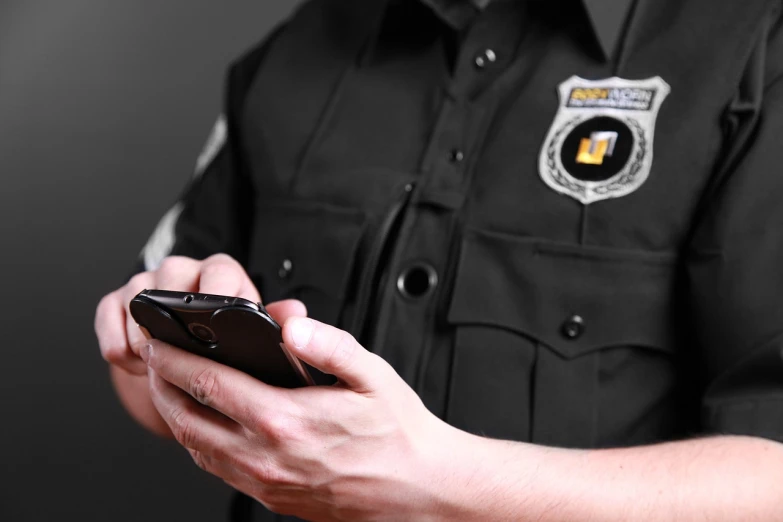 a close up of a person holding a cell phone, a digital rendering, by Niko Henrichon, shutterstock, police uniform, in black uniform, professional closeup photo, badge on collar