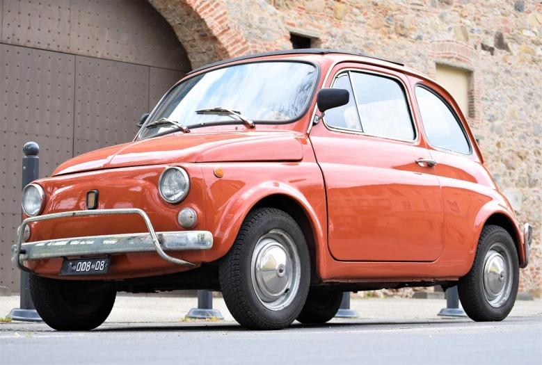 a small red car parked in front of a brick building, a portrait, inspired by Francesco Filippini, shutterstock, renaissance, 60s style, orange, anato finnstark. front view, very crisp details