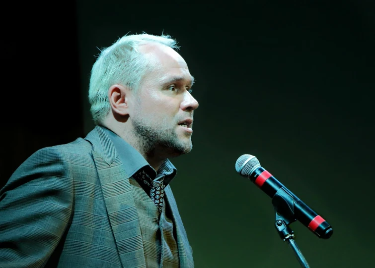 a man in a suit speaking into a microphone, by Pavel Fedotov, billy corgan, journalistic photo, oleg bulakh, richard garriott