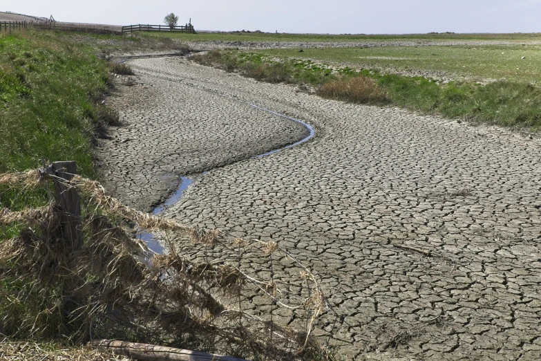 a river running through a dry grass covered field, by Erwin Bowien, cracks, highly detailed picture, irrigation, full shot photo