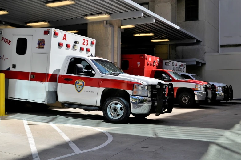 a couple of ambulances parked next to each other, set inside of parking garage, white and red body armor, 3 4 5 3 1, portrait shot