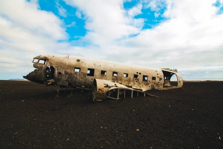 a plane that is sitting in the dirt, hurufiyya, covered with tar. dslr, iceland landscape, burned city, tourist photo