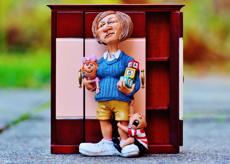 a figurine of a woman holding a doll, a picture, by senior artist, pixabay contest winner, naive art, wooden cabinet, 3 doors, [ realistic photo ]!!, funny cartoonish