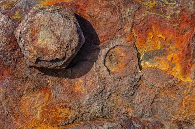 a close up of a rock with a bolt on it, by Arnie Swekel, shutterstock contest winner, auto-destructive art, rusted panels, vibrant hues, circle forms, ochre ancient palette