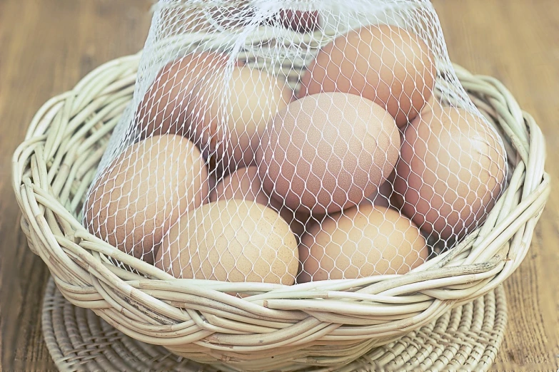 a basket filled with eggs sitting on top of a wooden table, a stock photo, by John Murdoch, packshot, netting, high res photo, close-up shot