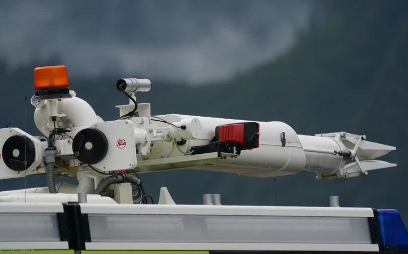 a white truck with a red light on top of it, military drone, 3 0 0 mm telephoto lens, side view close up of a gaunt, swiss