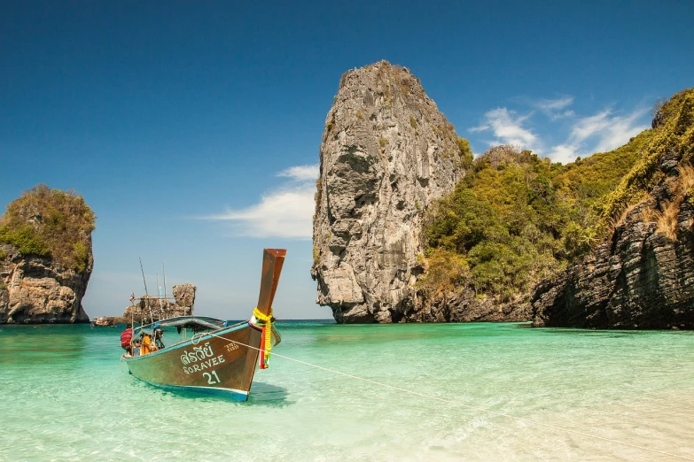 a boat that is sitting in the water, a picture, by Richard Carline, shutterstock, thailand, the rock is in the sea, white sandy beach, cover shot