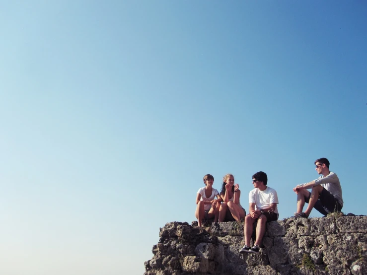 a group of people sitting on top of a rock, a picture, figuration libre, summer feeling, header, mid shot photo