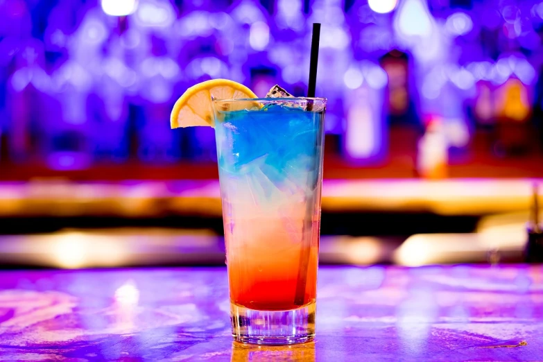 a colorful drink sitting on top of a wooden table, a stock photo, by Joe Bowler, pexels, blue and yellow lighting, server, strong blue and orange colors, 21 years old