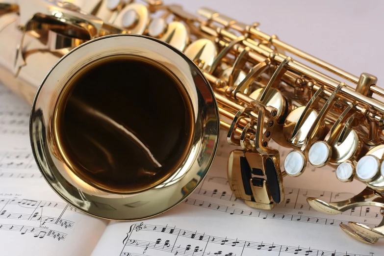 a saxophone sitting on top of a sheet of music, saxophones, shiny brass, music being played, more details