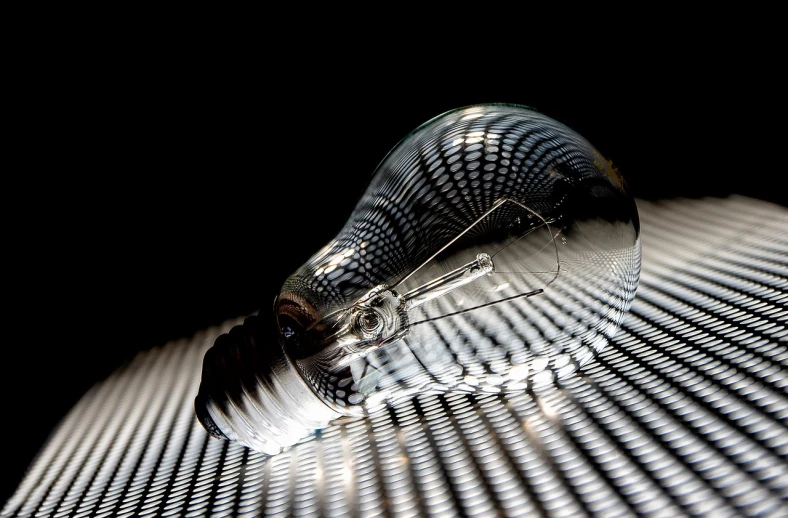 a light bulb sitting on top of a table, a stipple, by Jon Coffelt, flickr, abstract illusionism, translucent glass shine, high angle close up shot, hyperrealistic!, ((still life))