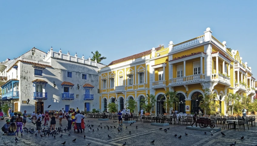 a group of people standing in front of a yellow building, baroque, tropical coastal city, patio, on a great neoclassical square, bird