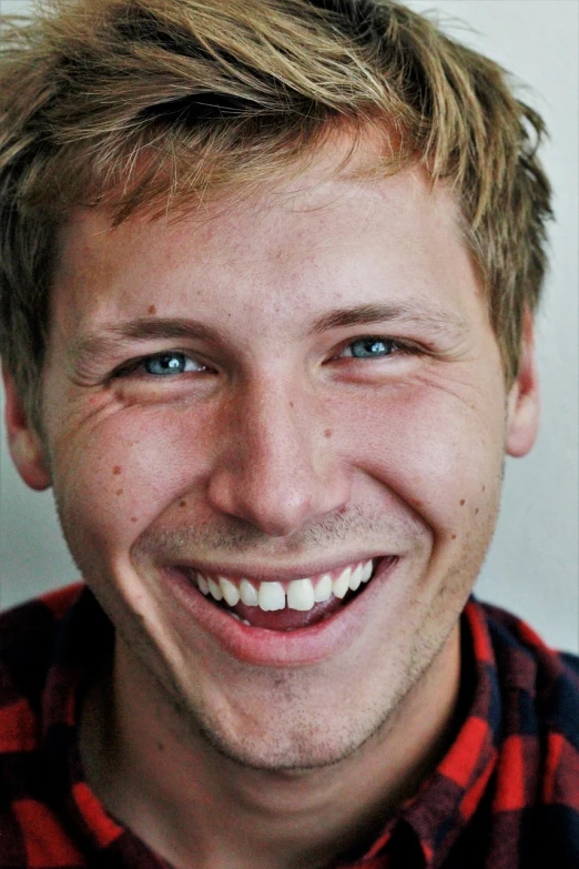 a close up of a person wearing a plaid shirt, a portrait, inspired by Samu Börtsök, unsplash, very huge smile, he looks like tye sheridan, blonde man, joe pera