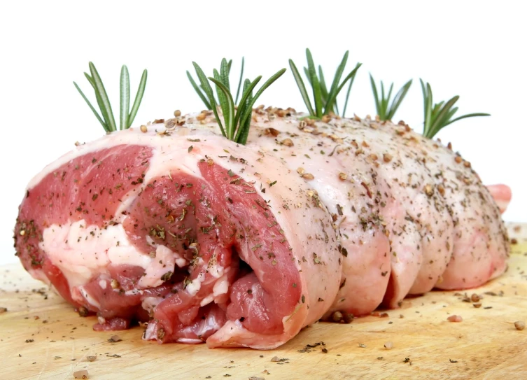 a piece of meat sitting on top of a wooden cutting board, by Samuel Scott, shutterstock, renaissance, human lamb hybrid, on a white background, herbs, foodphoto