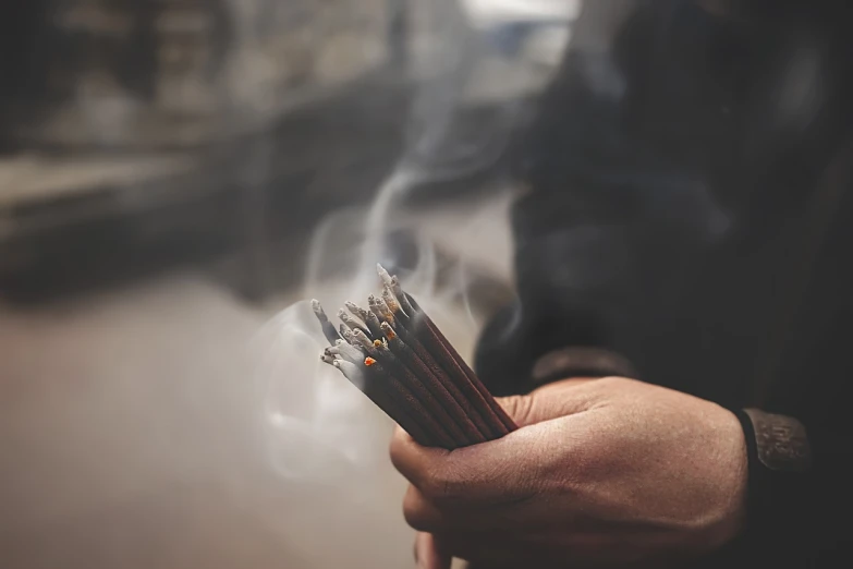 a person holding a bunch of pencils in their hands, incense, calm atmosphere, detailed bushido form smoke, 🕹️ 😎 🚬