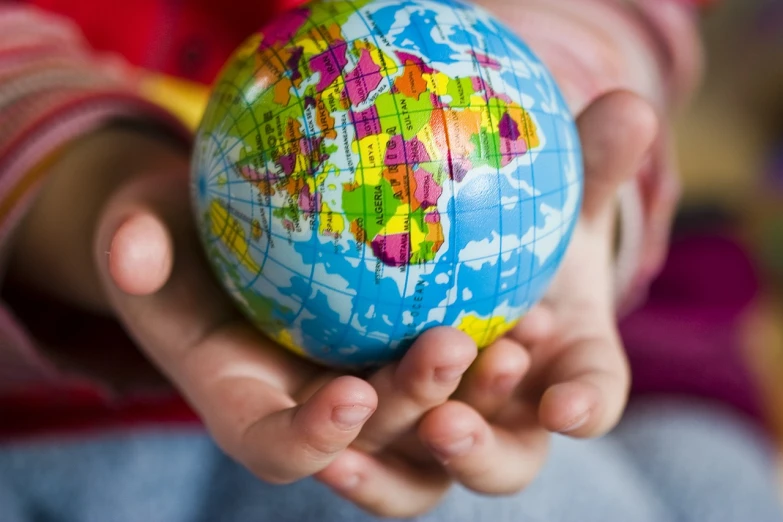 a person holding a small globe in their hands, siblings, istockphoto, closeup of arms, a brightly coloured