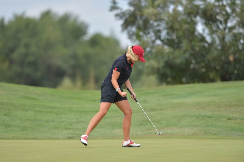 a woman putting a putt on a golf course, by Caroline Mytinger, flickr, wearing red shorts, utah, triumphant pose, student