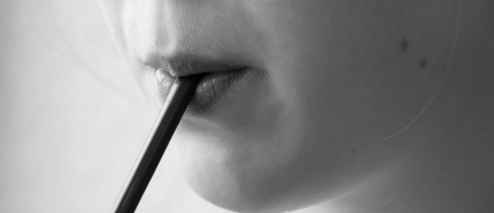 a close up of a person with a toothbrush in their mouth, a charcoal drawing, by Thomas Häfner, pexels, putting on lipgloss, in a quiet moment, round chin black eyeliner, with a straw