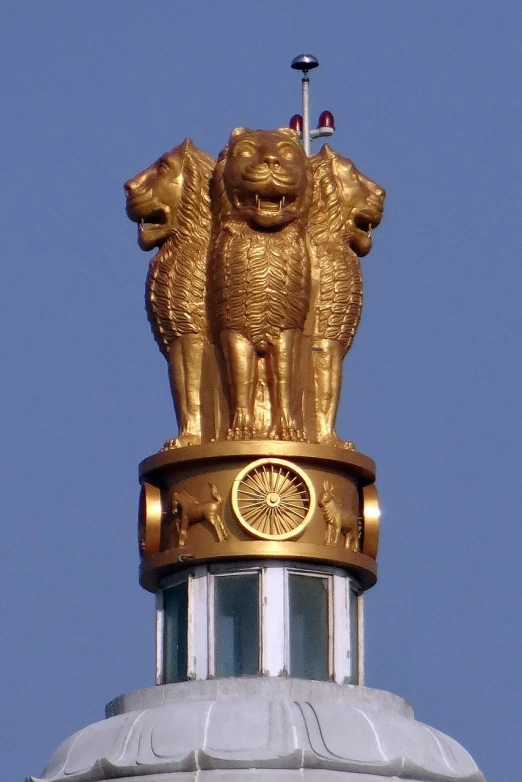 a golden statue of lions on top of a building, an art deco sculpture, inspired by Sir Jacob Epstein, flickr, indian flag, crystal column, centred in image, assamese
